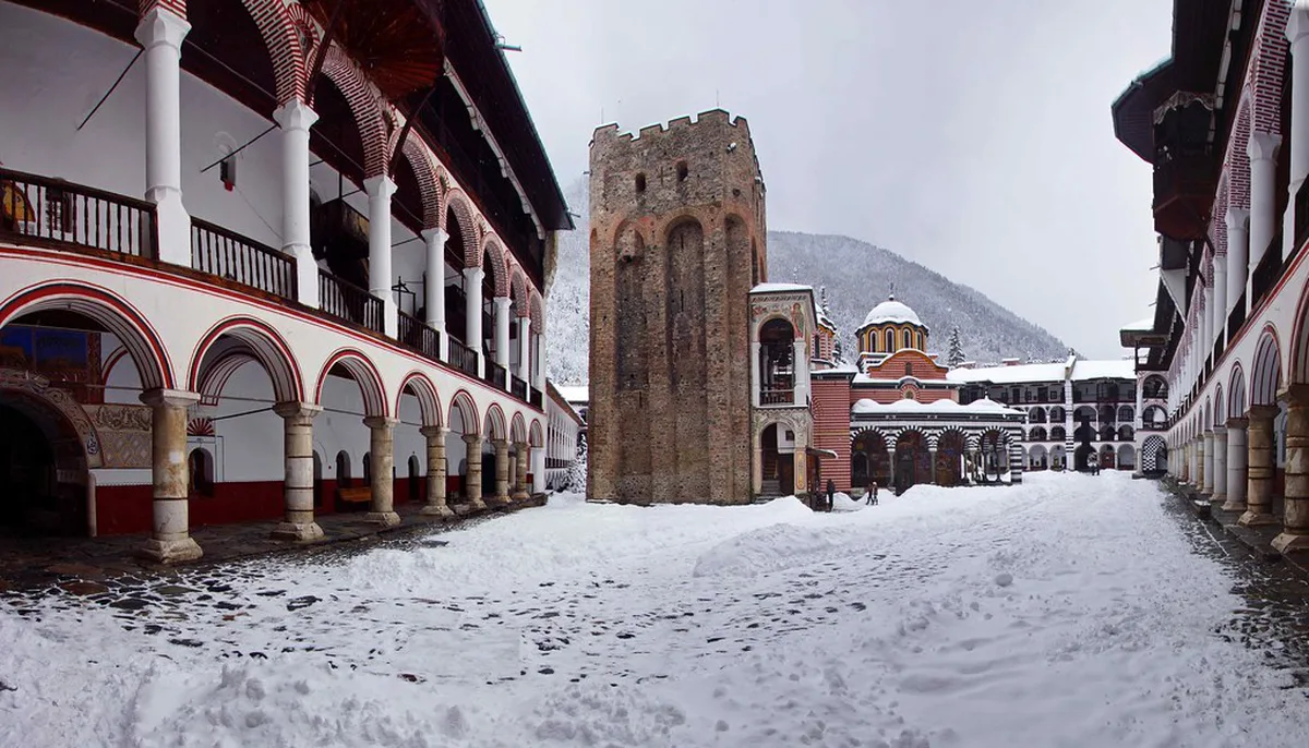 The arches and courtyard of Rila Monastery blanketed in snow during a Bulgarian winter